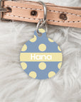 Dog collar with a blue and yellow polka dot tag on a fluffy white background